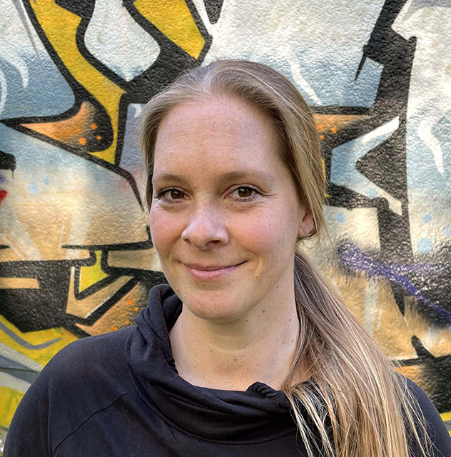 Die Autorin Enka Wiese steht vor einer Graffitiwand.