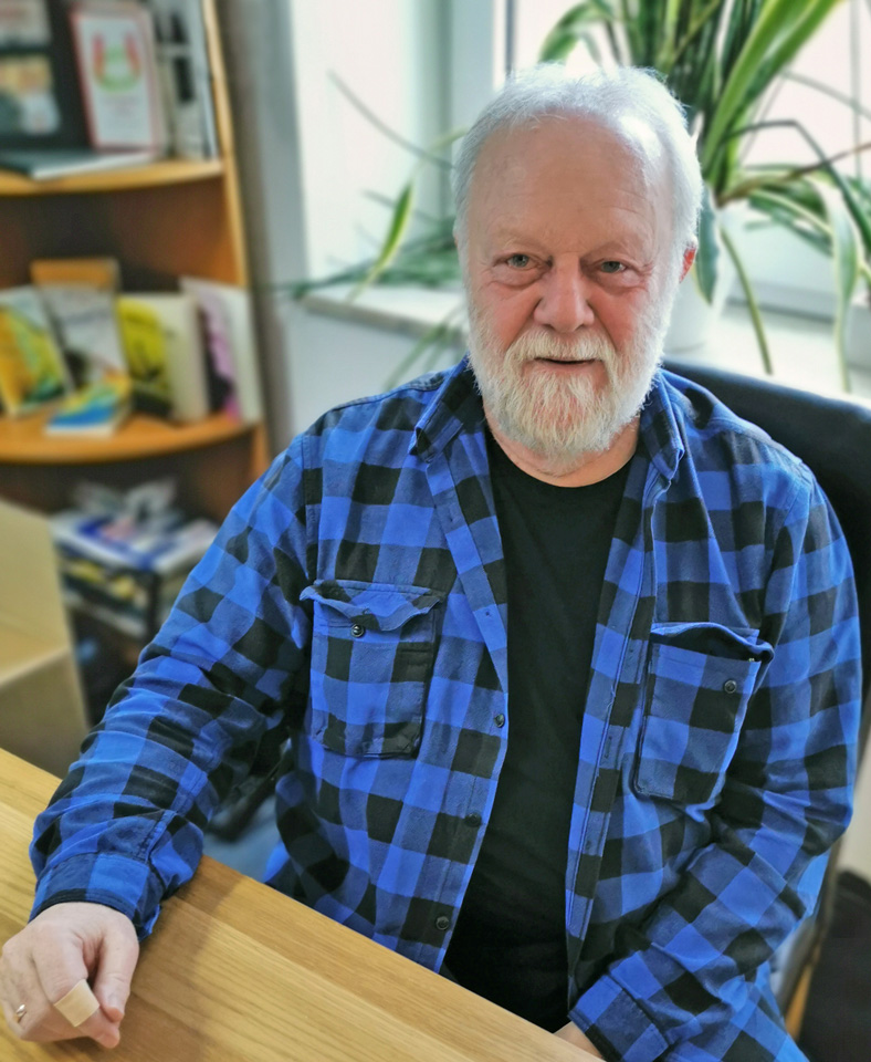 Der Autor Winfried Thamm sitzt an einem Tisch im OCM Verlag.