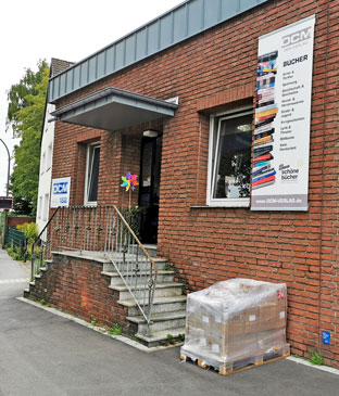 Vor der Tür des OCM Verlags steht eine Palette mit Büchern.